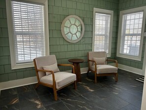 A room with two armchairs, a round table, and a decorative wall piece.