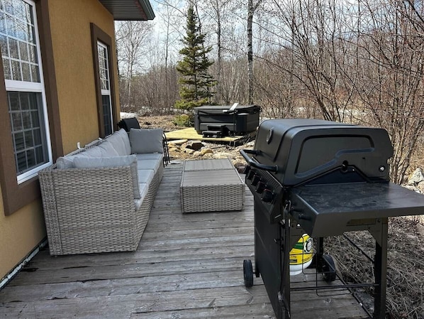Eine Terrasse mit Gartenmöbeln, einem Grill und einem Fernseher.