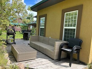 An outdoor patio with a wicker sofa, a table, and chairs.