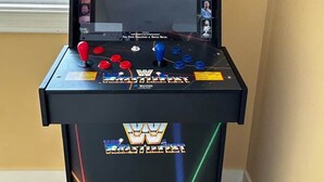 Eine Ringkampf-Spieltrommel mit Bildschirm, Joystick, Knöpfen und einem Logo.