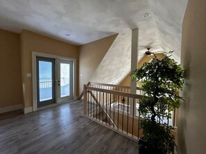 Une pièce spacieuse avec un plancher en bois, un escalier et une grande fenêtre.