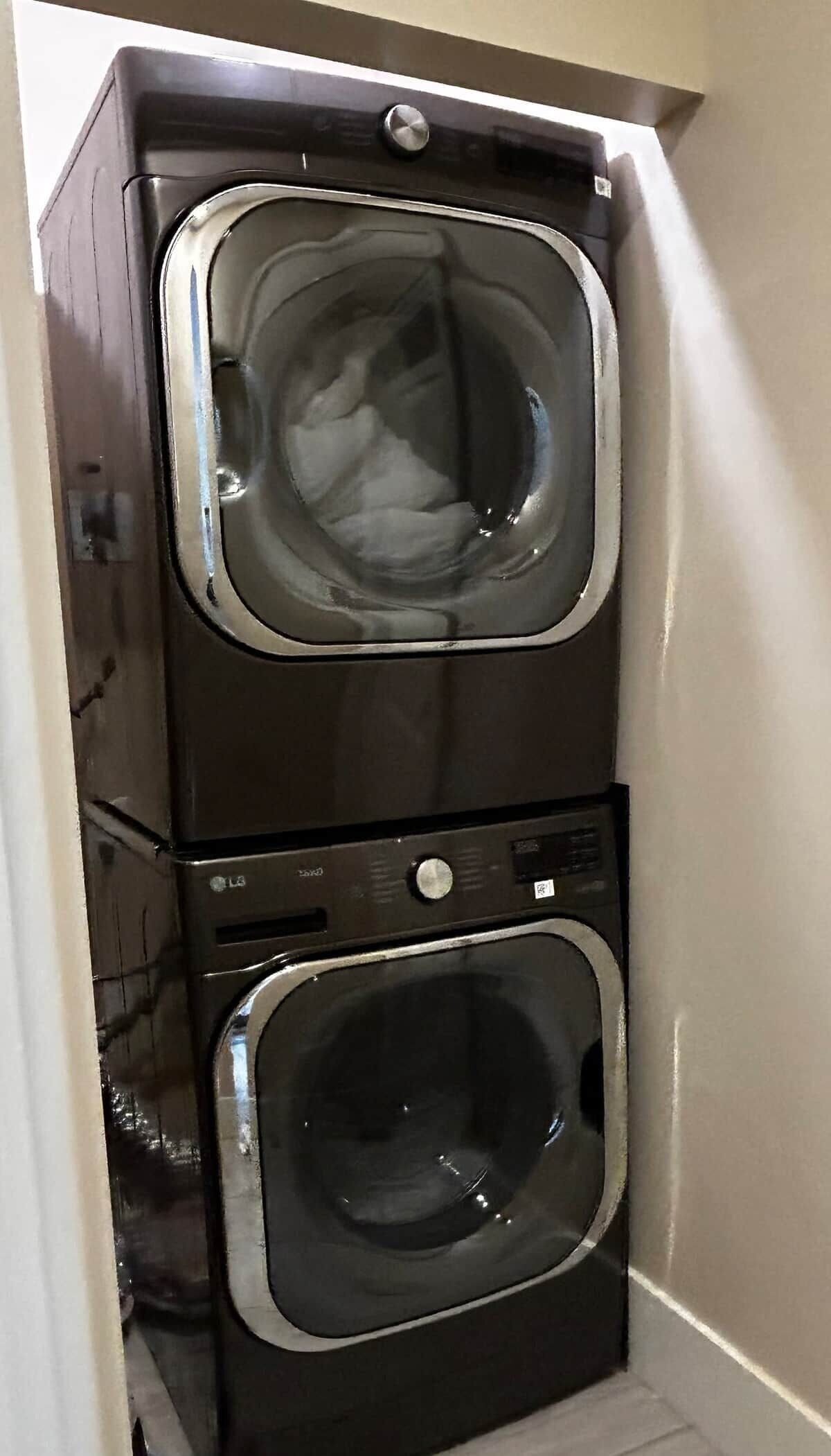 A stacked washer and dryer unit in a corner of a room.