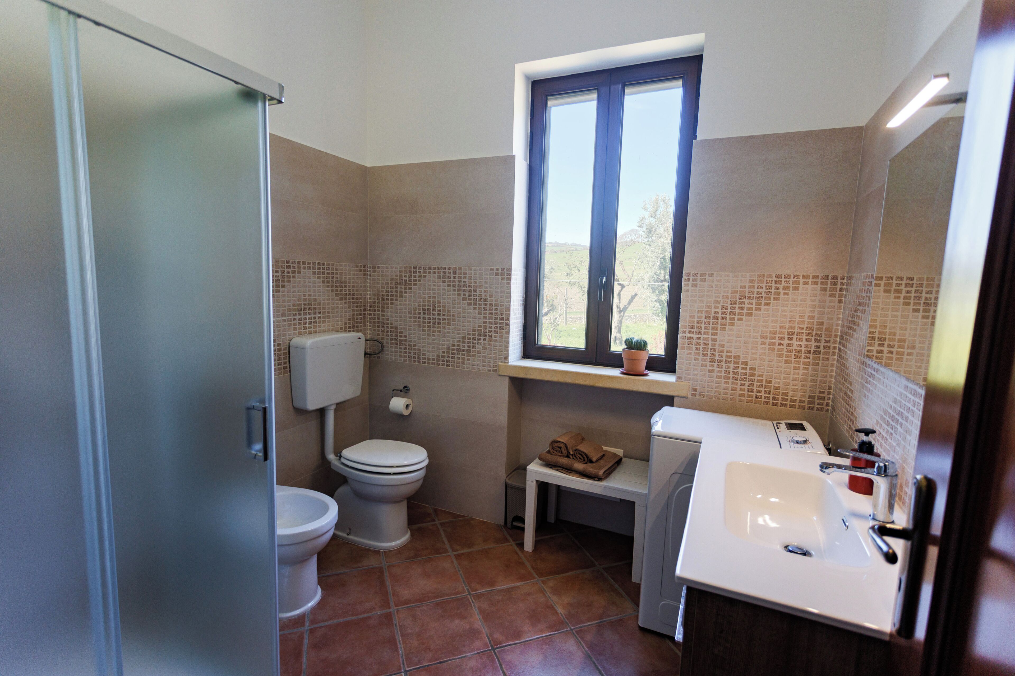 Une salle de bain avec des toilettes, un lavabo et une fenêtre.