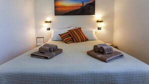 A hotel room with a bed, pillows, and towels. There is a painting on the wall above the bed. - Villa Cisura Ranne - 2 km from the sea with a private heated pool (Puglia)