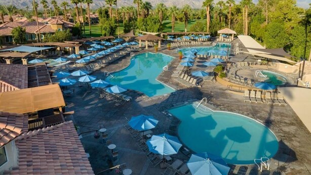 Ein Resort mit mehreren Schwimmbecken, Liegebereichen und Palmen.