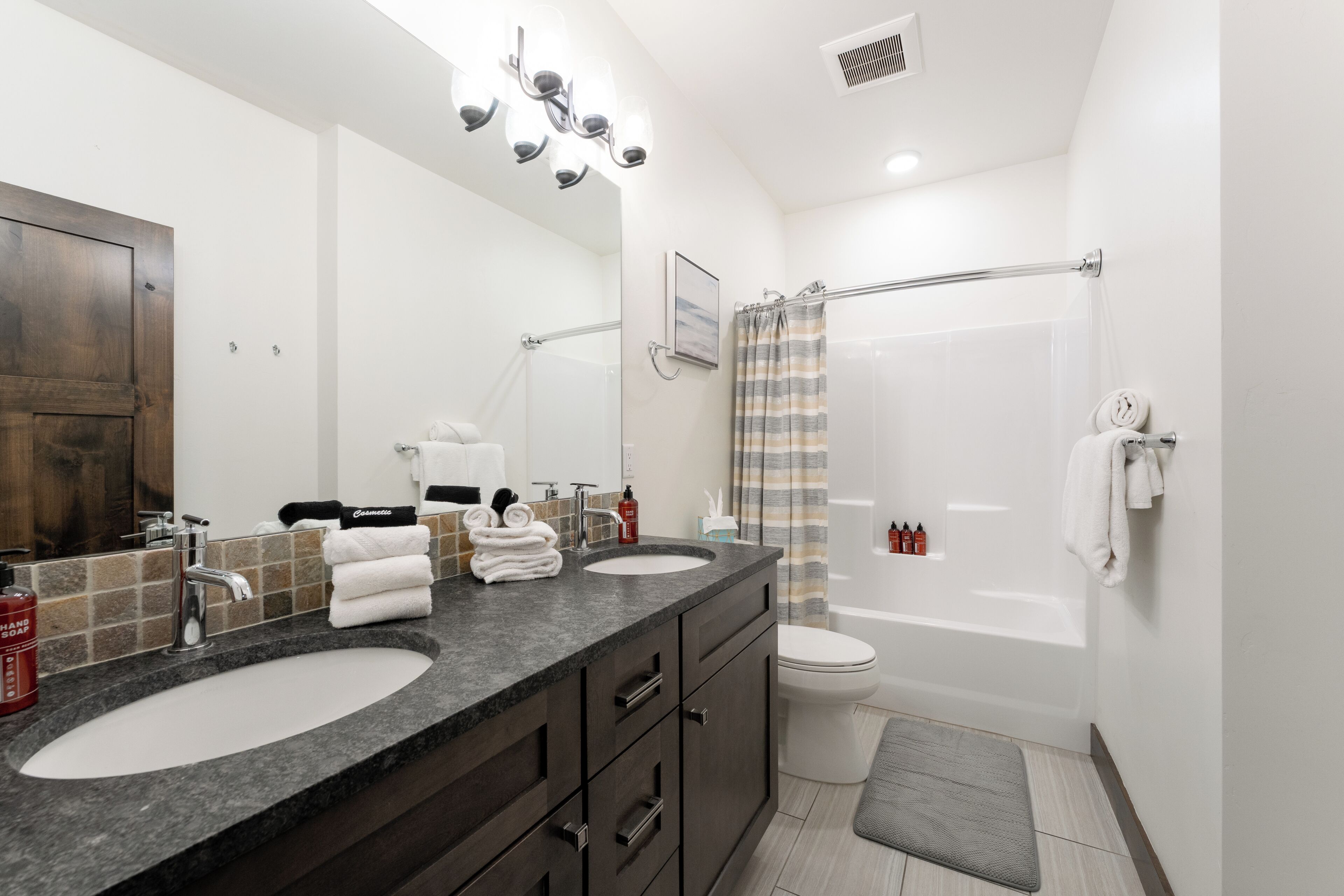 A bathroom with two sinks, a toilet, a bathtub, and a shower curtain.