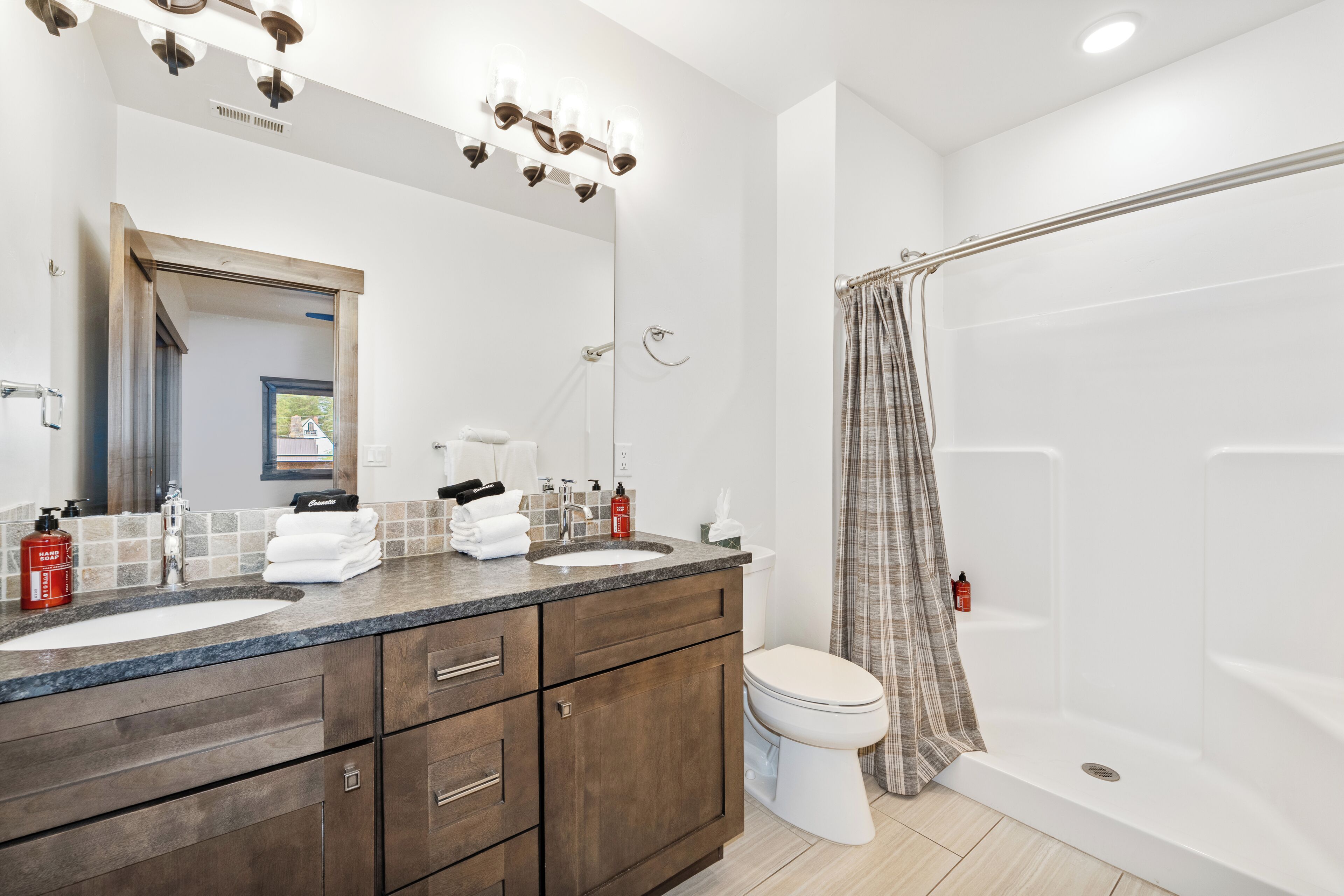 A bathroom with two sinks, a toilet, and a shower.