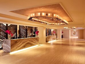 Eine großzügige Lobby mit einer Marmor-Rezeption, modernen Leuchten und dekorativen Vasen mit Blumen.