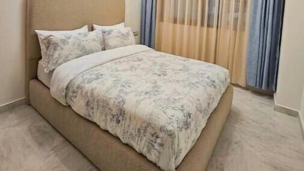 Un dormitorio con cama, cortinas y una lámpara en el techo.