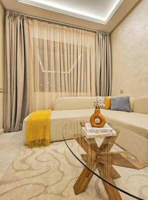 A living room with a sofa, a glass coffee table, and a yellow throw blanket. - Modern 2-Bedroom Apartment – Near Downtown (Tanger)