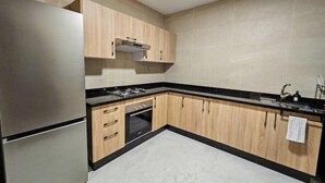Una cocina con armarios de madera, un refrigerador de acero inoxidable y una encimera negra.