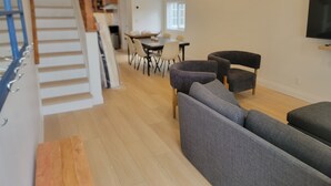 A modern living room with a staircase, a dining area, and a TV mounted on the wall. - Stay in the heart of Toronto (toronto)