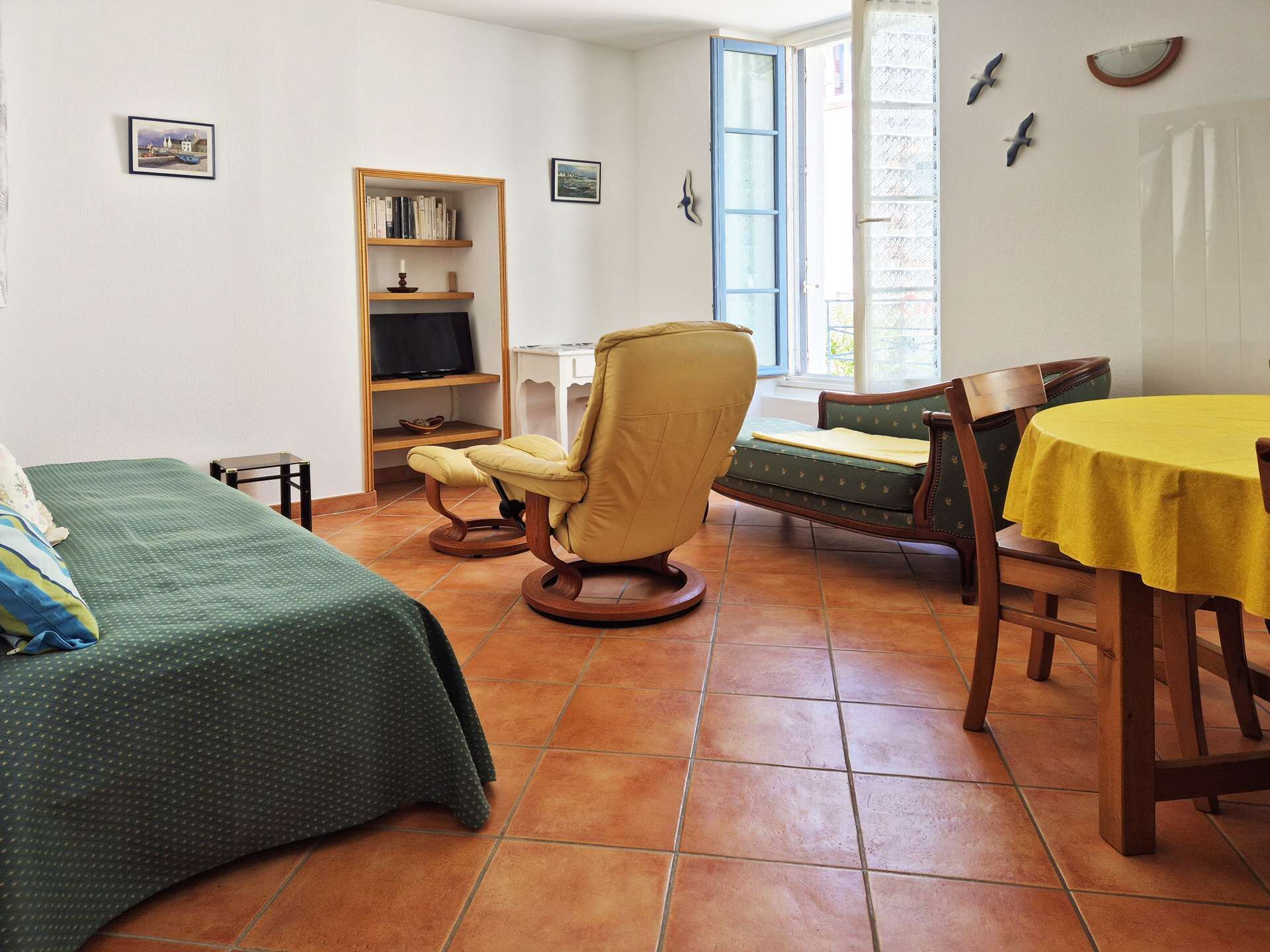 Una stanza con un letto, una sedia, un tavolo, una libreria e una finestra.