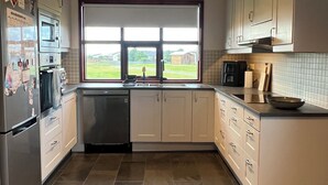 A modern kitchen with stainless steel appliances, a dishwasher, and a window with a view of the outdoors.