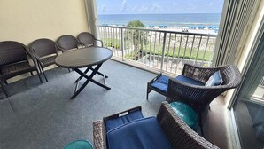 En balkon med fletmøbler, et rundt bord og udsigt til stranden.