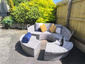 A wicker outdoor seating area with cushions and a bottle. - Owl (Pickering)