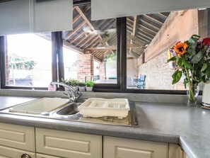 A kitchen with a sink, a dish rack, and a vase with flowers. - Owl (Pickering)