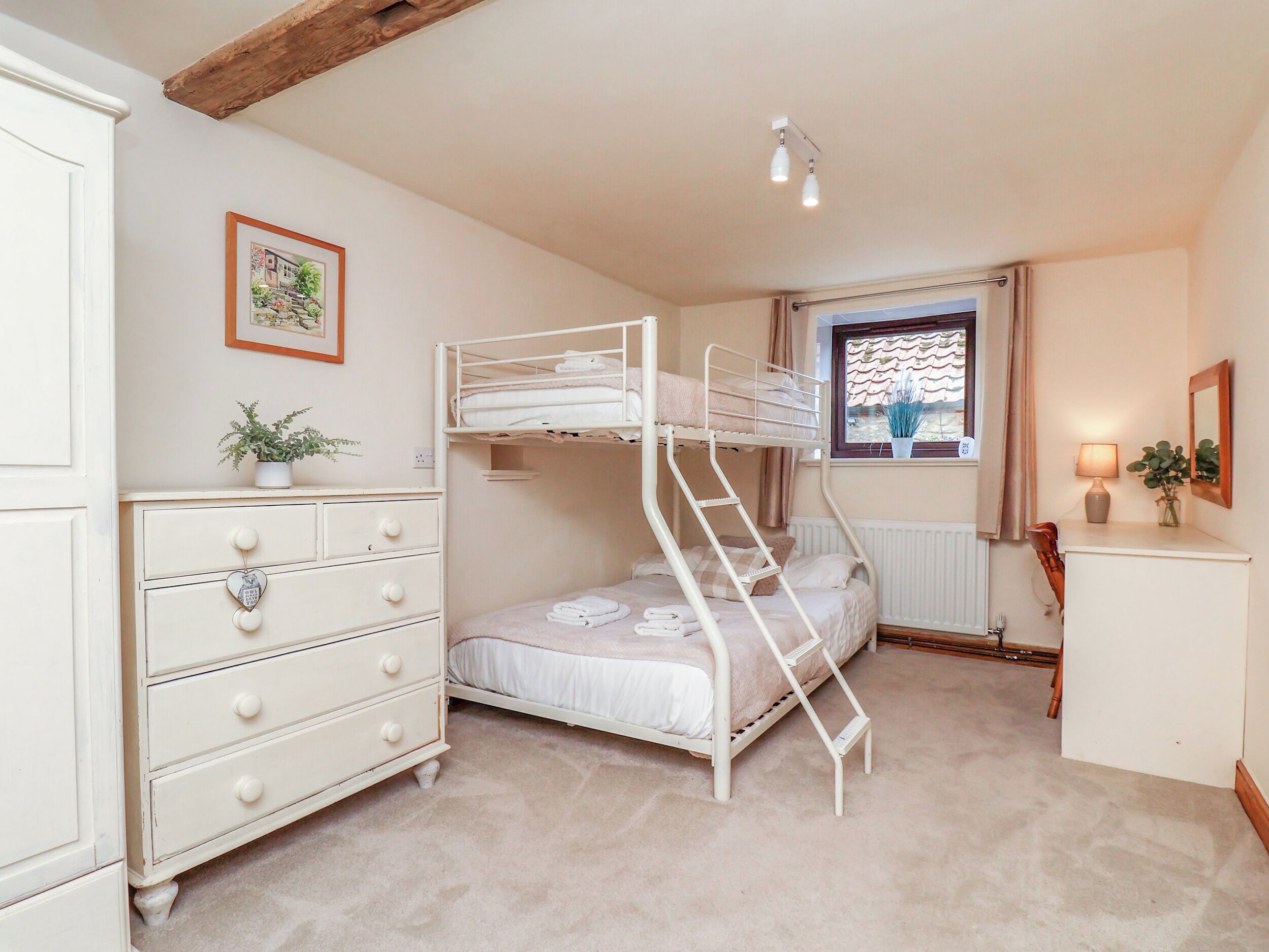 A bunk bed room with a dresser, a window with curtains, and a radiator.