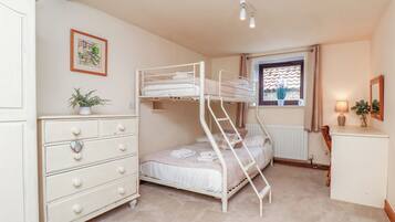 A bunk bed room with a dresser, a window with curtains, and a radiator.