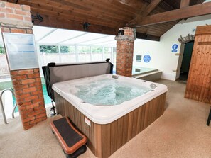 A hot tub in a covered area with a wooden bench, a brick pillar, and a sign indicating a spa pool. - Owl (Pickering)