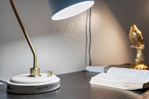 Una làmpada de taula amb port de càrrega USB, un llibre i un objecte decoratiu.