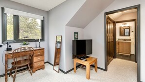 Ein Zimmer mit Schreibtisch, Stuhl, Fernseher und Spiegel.