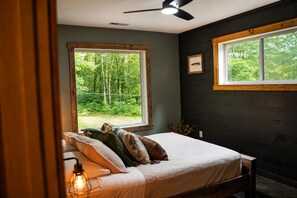 Ein Schlafzimmer mit Bett, Fenster, Deckenventilator und einem an der Wand hängenden Bild.