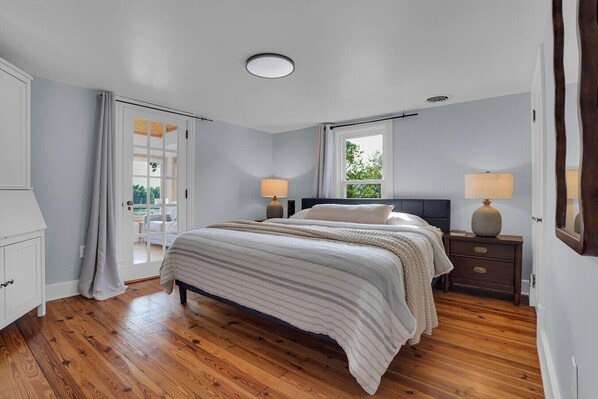 A bedroom with a bed, bedside tables, a window, and a door. - Riverfront Manor - Beautiful view and setting! (Dauphin)