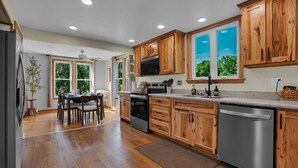 A kitchen with wooden cabinets, stainless steel appliances, and a dining area with a table and chairs. - Riverfront Manor - Beautiful view and setting! (Dauphin)