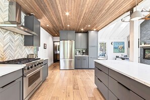A modern kitchen with a herringbone-patterned backsplash, stainless steel appliances, and a wooden ceiling. - Sierra Sanctuary by Tahoe Getaways - Beautiful 5BR w/ Hot Tub & Private Outdoor Area (Truckee)