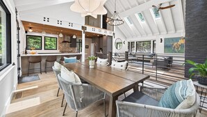 Una sala da pranzo spaziosa con tavolo in legno e sedie in vimini, una cucina con elettrodomestici moderni e un'ampia finestra con vista sul verde.