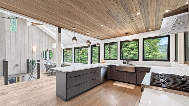 Una cucina moderna con una grande isola, pavimento in legno e ampie finestre che offrono vista sul panorama esterno.