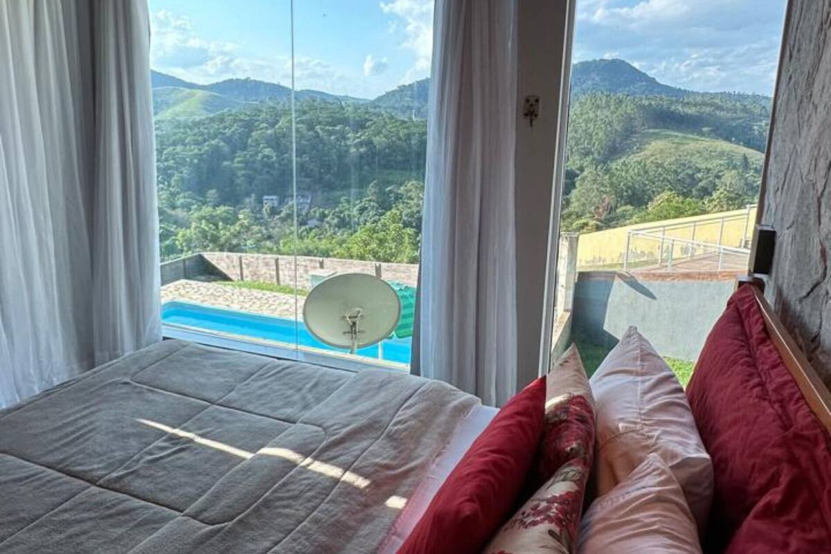 A bedroom with a bed, curtains, and a view of a mountainous landscape.