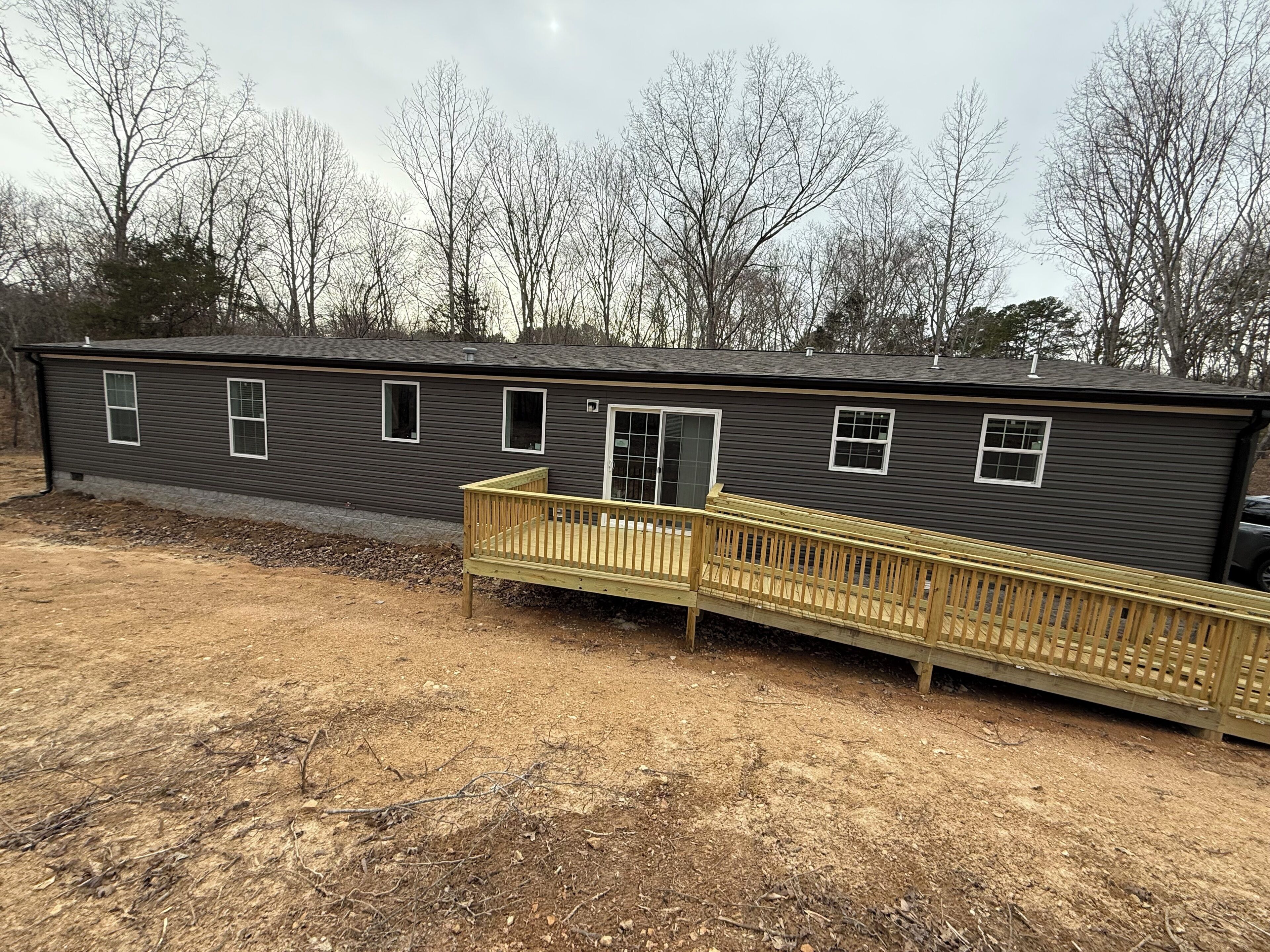 A single-story building with a front deck, a sliding glass door, and multiple windows.