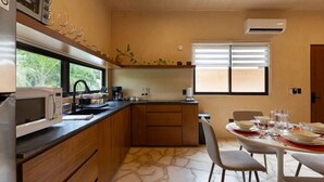 A compact kitchen with a microwave, coffee maker, and a dining area with a table set for two. - Depto. Eek’ · 1 Hab · 1 Baño · Terraza Privada (Merida)