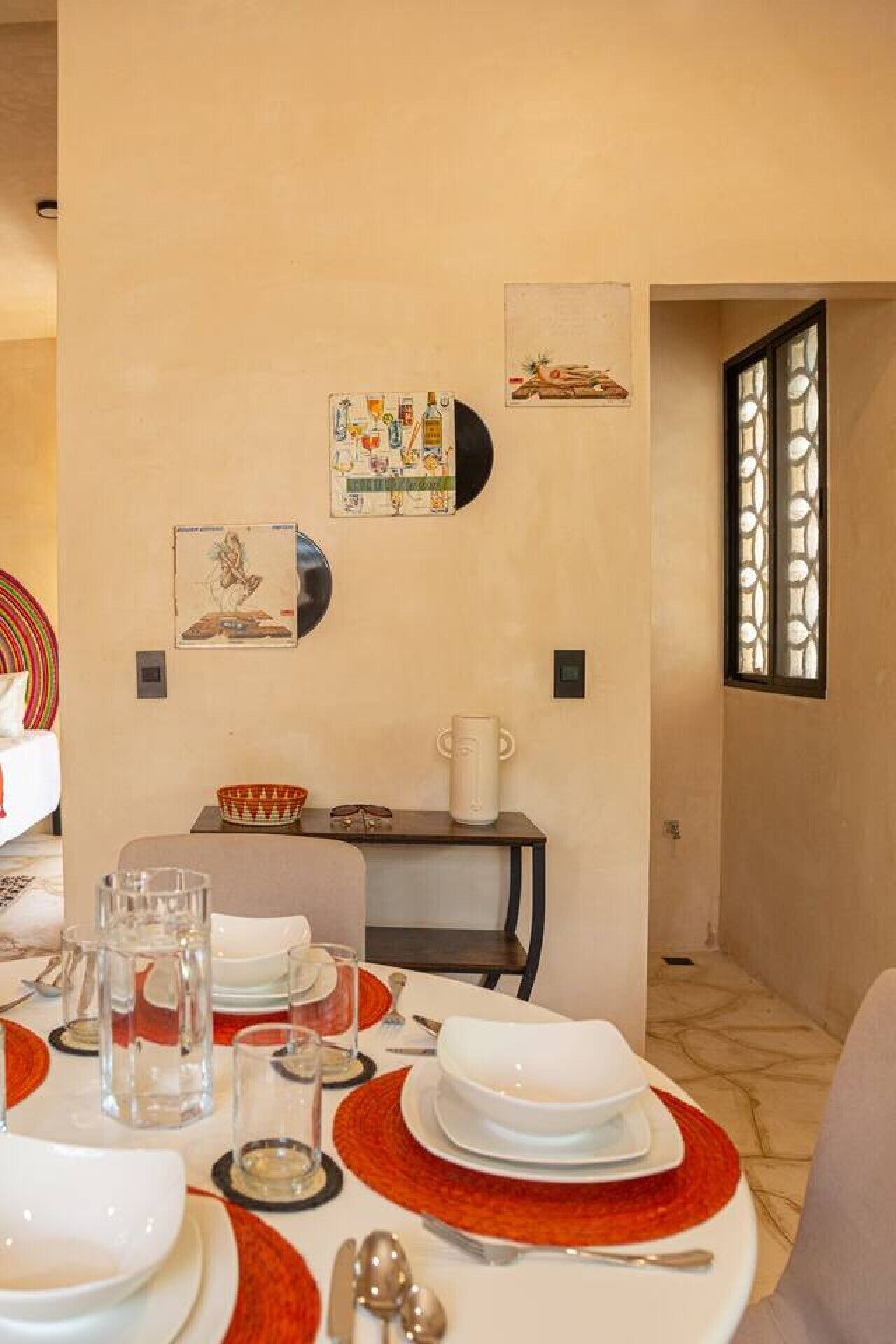 A dining area with a table set for four, a coffee pot, and wall art.