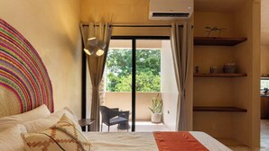 A bedroom with a bed, a balcony with a chair, and a potted plant. - Depto. Eek’ · 1 Hab · 1 Baño · Terraza Privada (Merida)