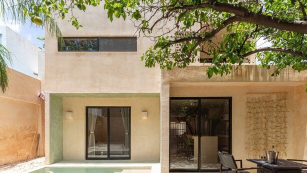 Een modern huis met een zwembad, een terras met tuinmeubilair, en een grote schuifpui.