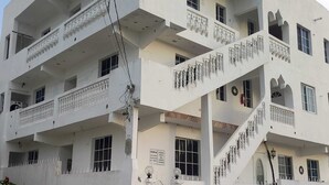 Un edificio de varios pisos con balcones, una escalera y un cartel que dice 'Mendez House'.