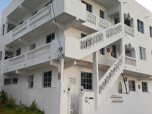 Un edificio de varios pisos con balcones, una escalera y un letrero que dice "Mendez House".