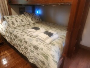 A bunk bed with a quilted bedspread featuring a pine tree pattern. There are two neatly folded towels on the bed.