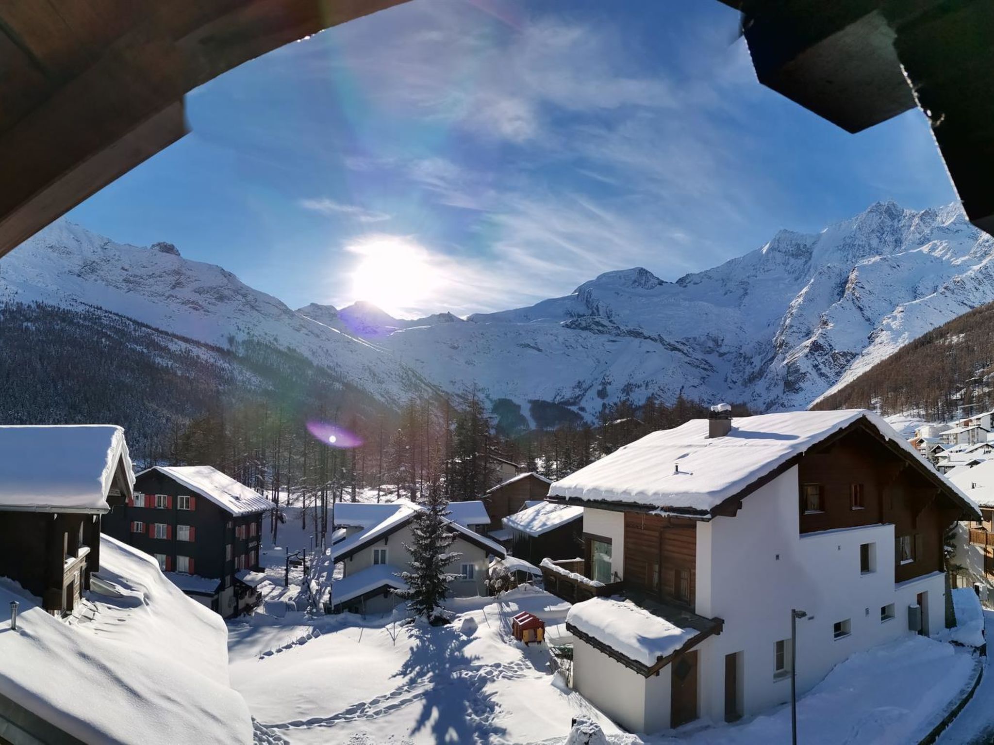 Een met sneeuw bedekt bergdorp met traditionele houten huizen en een helder uitzicht op de omliggende toppen.