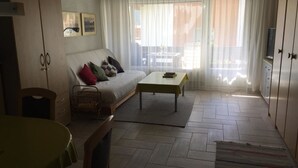 A living room with a sofa, a coffee table, a TV, and a dining area. - Amici 13 Appartement/Fewo 2-Bettwohnung by Interhome (Saas-Fee)