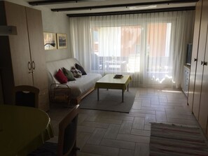 Ein Wohnzimmer mit Sofa, Couchtisch, Fernseher und Essbereich.