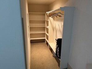 Un armario espacioso con amplios estantes y barra para colgar.