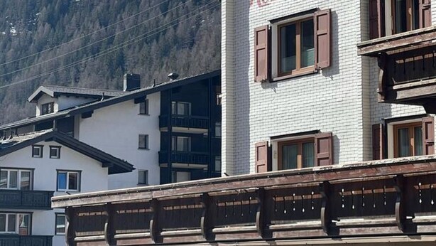 Ein Gebäude mit einem Schild, auf dem 'Rosehein' steht, und einem Berg im Hintergrund.