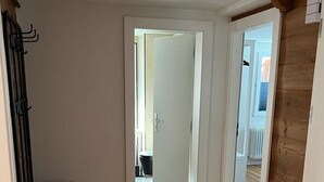 Ein Flur mit Holzdielen, einer Bank und einer Tür zu einem weiteren Raum.