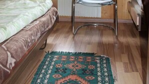 Een kamer met een bed, een stoel, een radiator en een raam met gordijnen.
