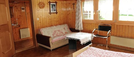 Una cabaña de madera con dos camas, una silla y una mesita.