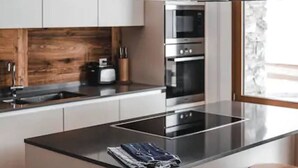A modern kitchen with a central island, stainless steel appliances, and wooden accents. - Sonnegg Lodge 2.2 Appartement/Fewo Appartement/Fewo by Interhome (Saas-Fee)